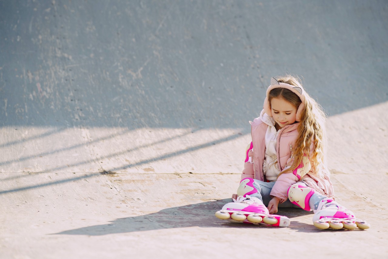 smiling-cute-child-in-roller-skates-sitting-on-skate-ramp-4127362.jpg